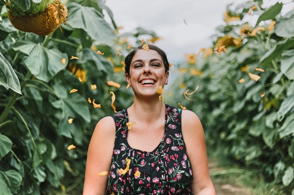 Gezonde vrouw loopt lachend door veld met zonnebloemen