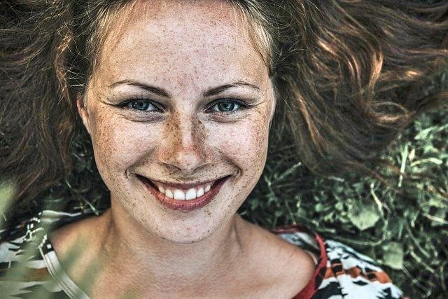 Veerkracht: vrouw ligt lachend in gras zonder stress